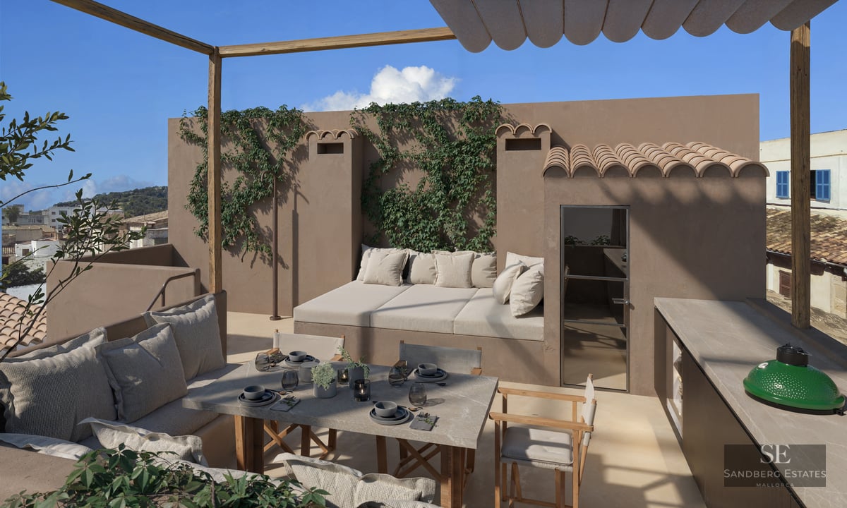 Sun-drenched rooftop terrace with a stone dining table, integrated daybed, outdoor kitchen, and climbing vines on stucco walls.