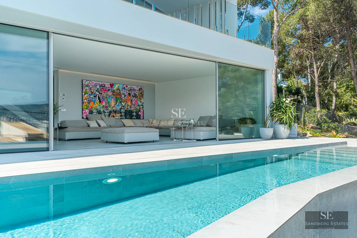 Bright living room with large windows, balcony with sea view, modern design, neutral color palette.