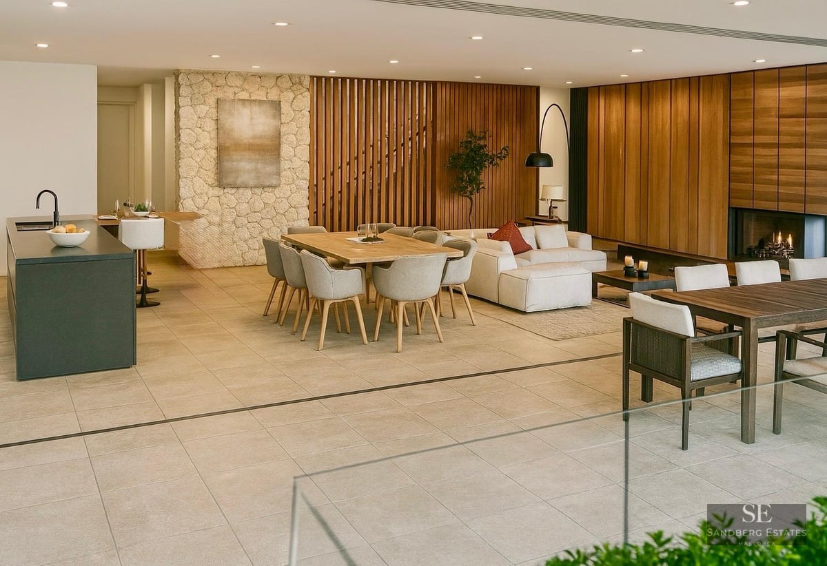 Modern open-plan room featuring sofas, dining tables, a stone feature wall, and fireplace under warm lighting.