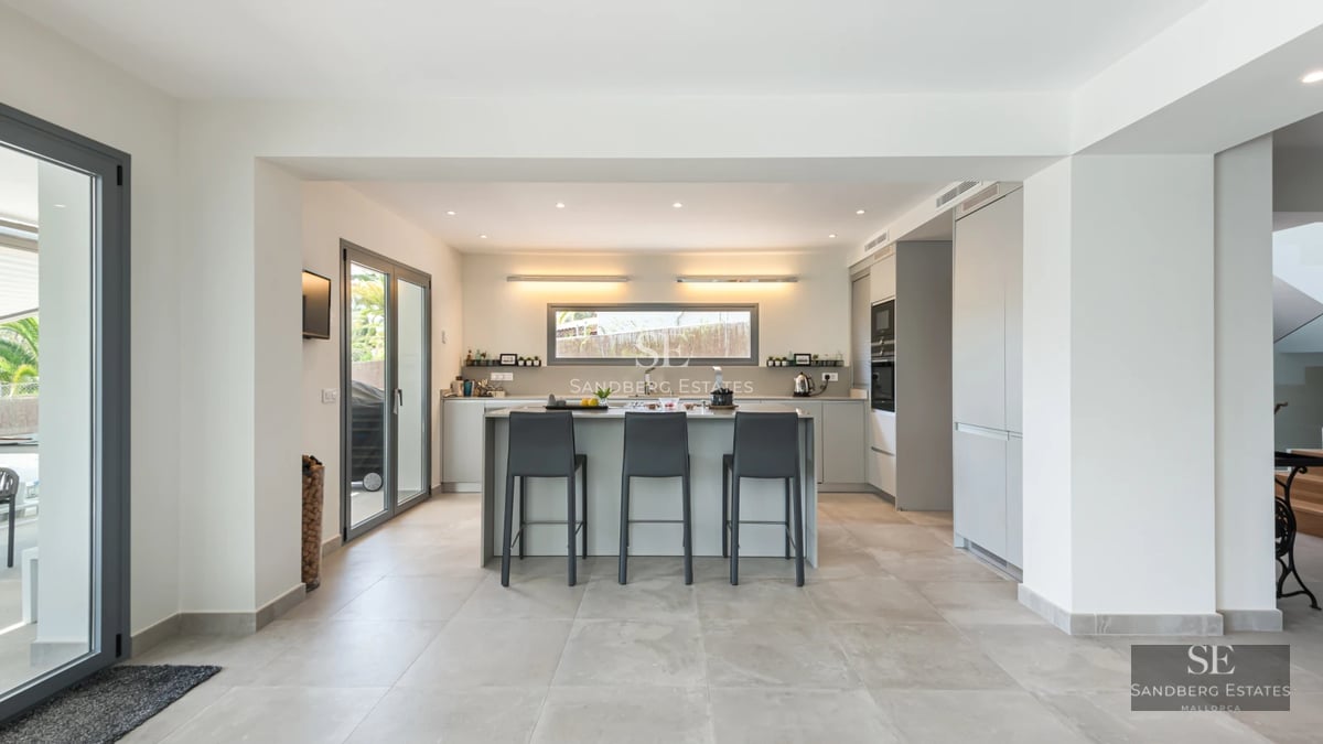 Bright living room with sea view, balcony, wood floors, and modern decor. Large windows and designer furniture.
