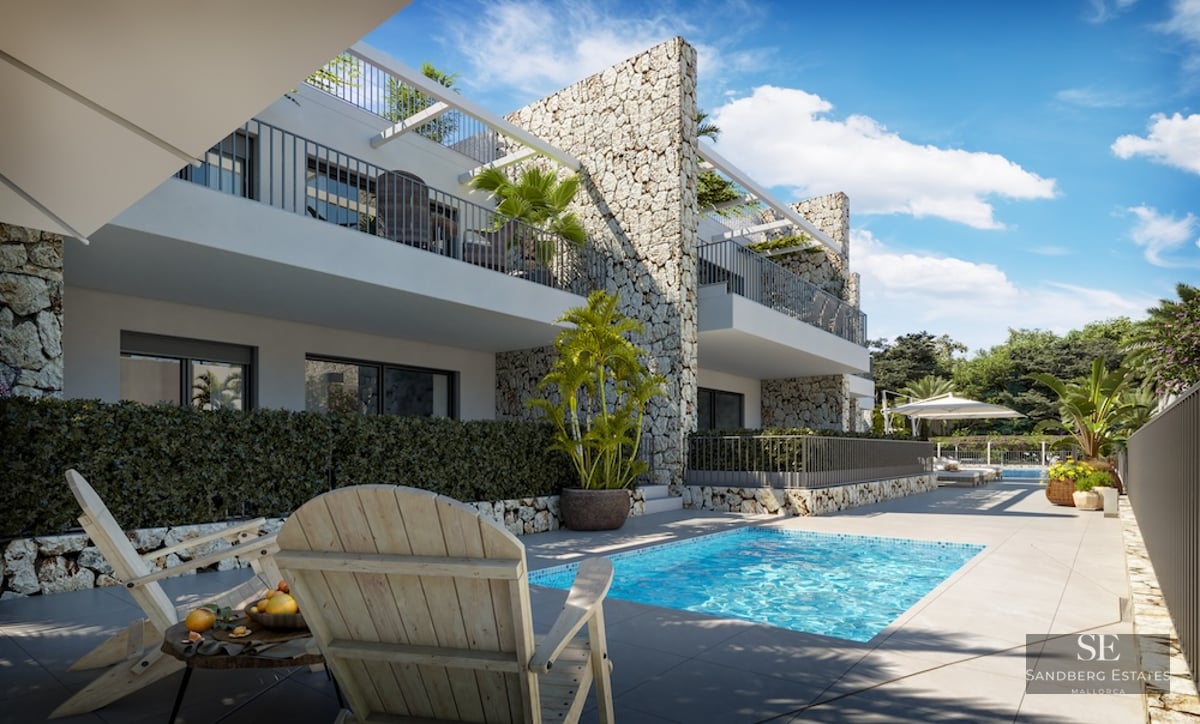 Modern swimming pool with wooden loungers and stone feature walls under a clear blue sky.