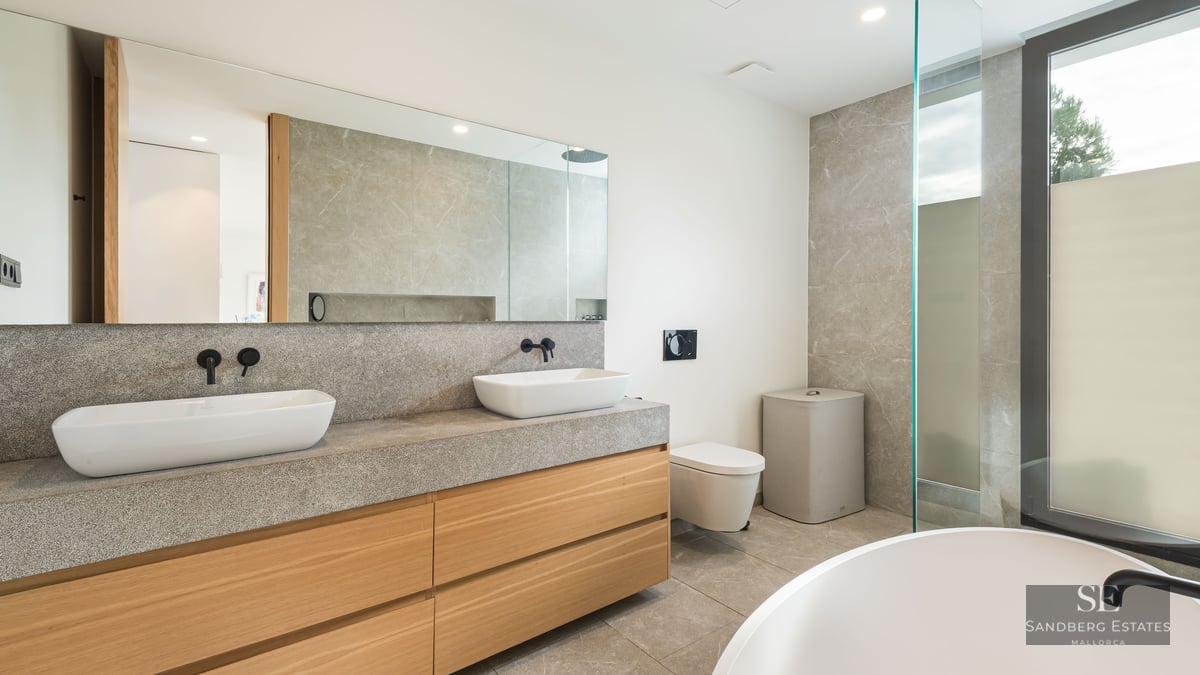 Salle de bain de luxe avec deux vasques sur un plan en pierre, meubles en bois et grand miroir.