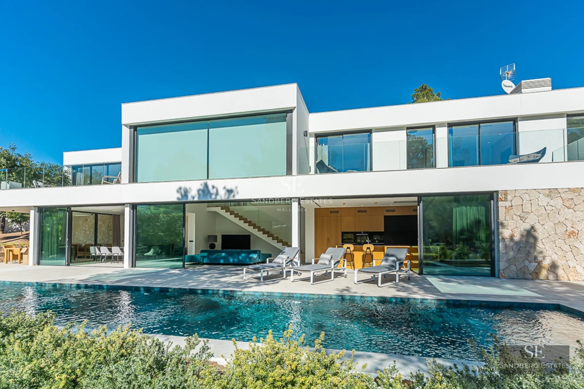 Vue extérieure d'une maison moderne avec piscine, jardin luxuriant et grandes fenêtres. Design élégant et finitions de haute qualité.