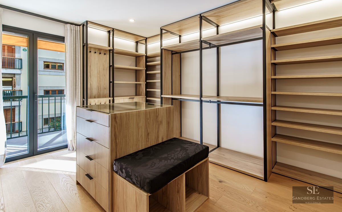 Dressing moderne avec étagères en bois clair, cadres en métal noir, un îlot central et accès au balcon.