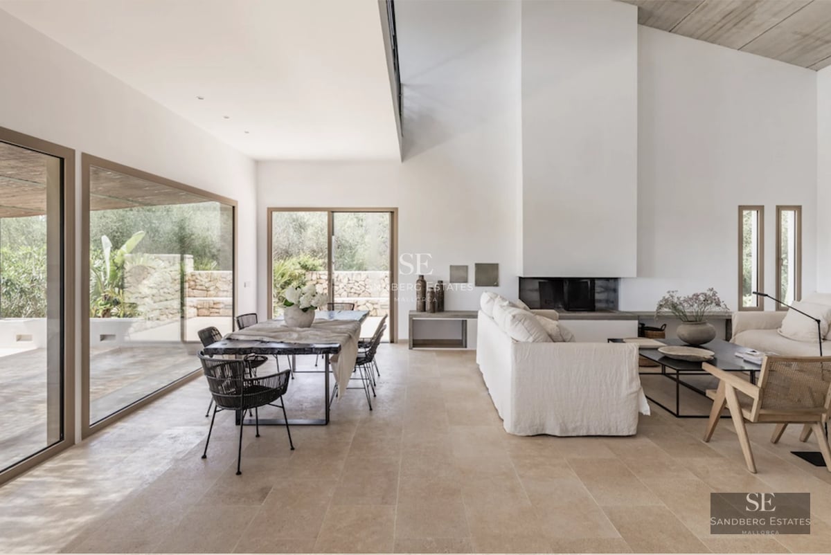 View of a luxury villa featuring an infinity pool, surrounded by lush gardens and expansive terraces. Modern design with window walls and natural stone.