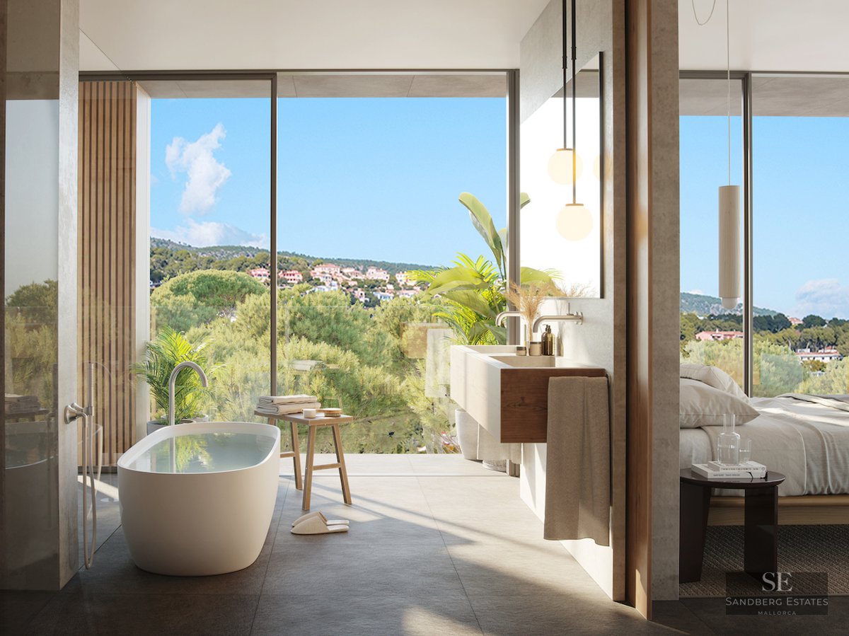 Luxury master bathroom featuring a freestanding tub, floating wood vanity, and floor-to-ceiling windows with forest views.