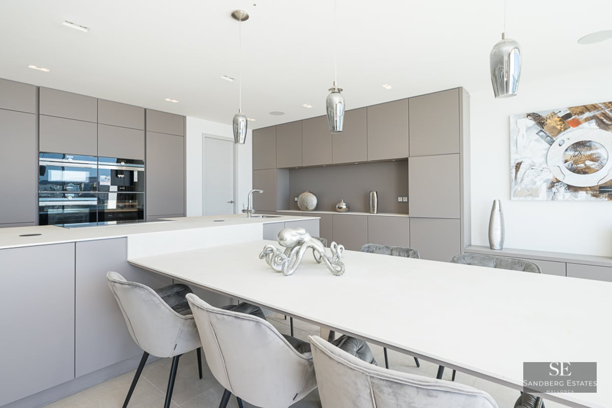 Contemporary kitchen with taupe cabinets, a large white island, and grey velvet dining chairs.