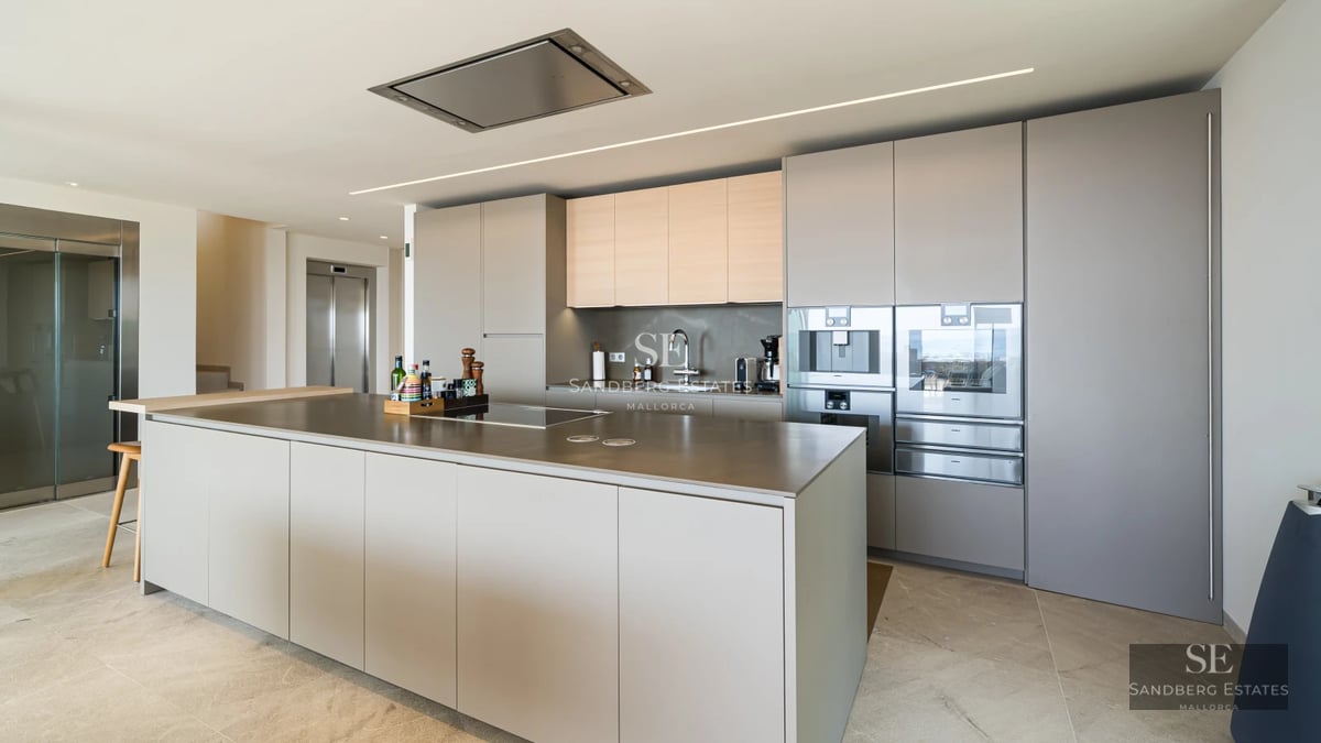 Spacious living room with floor-to-ceiling windows, sea view, light wood floors and modern designer furniture. Abundant natural light.