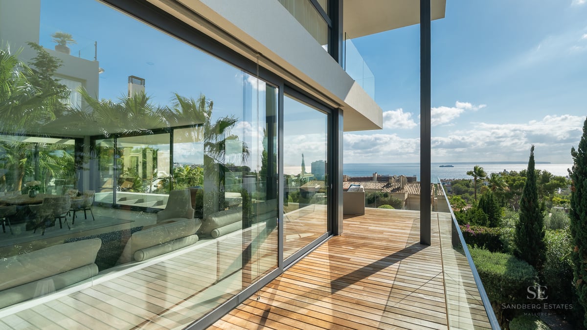 Modern wooden terrace with glass railings and panoramic views of the Mediterranean Sea.