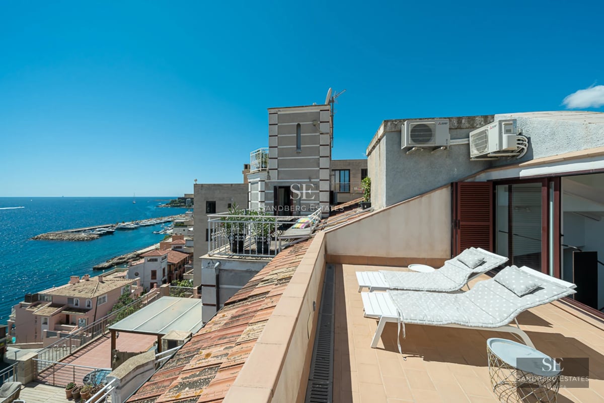 Modern balcony with glass railing, sea view, and minimalist furniture. Elegant design featuring light wood and plants.