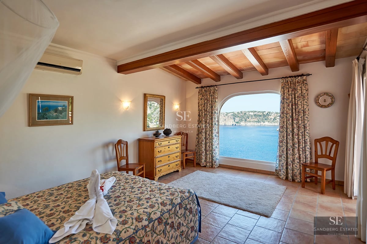 Spacious living room with picture windows, light wood floors, and modern design. Gray sofa and pool view.