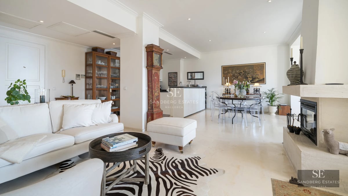 View of a modern living room with a balcony and sea view. Elegant furniture, wooden floors, and plenty of natural light.