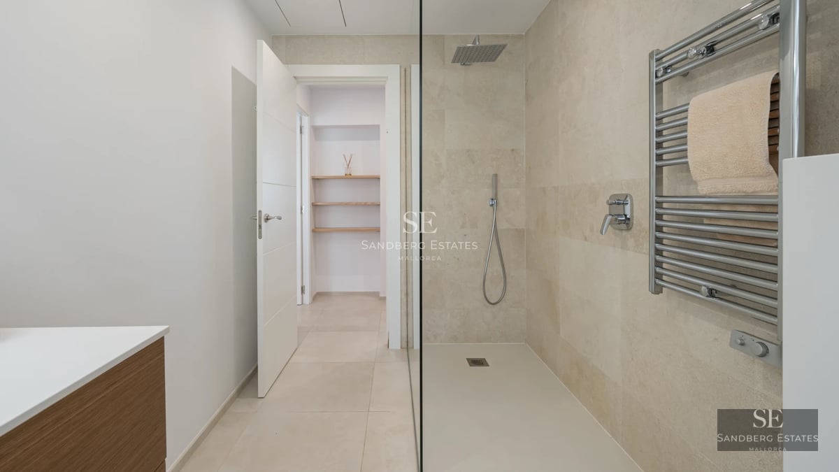 Spacious balcony with panoramic sea views. Modern outdoor furniture. Glass railing. Decorative plants. Wooden floors.