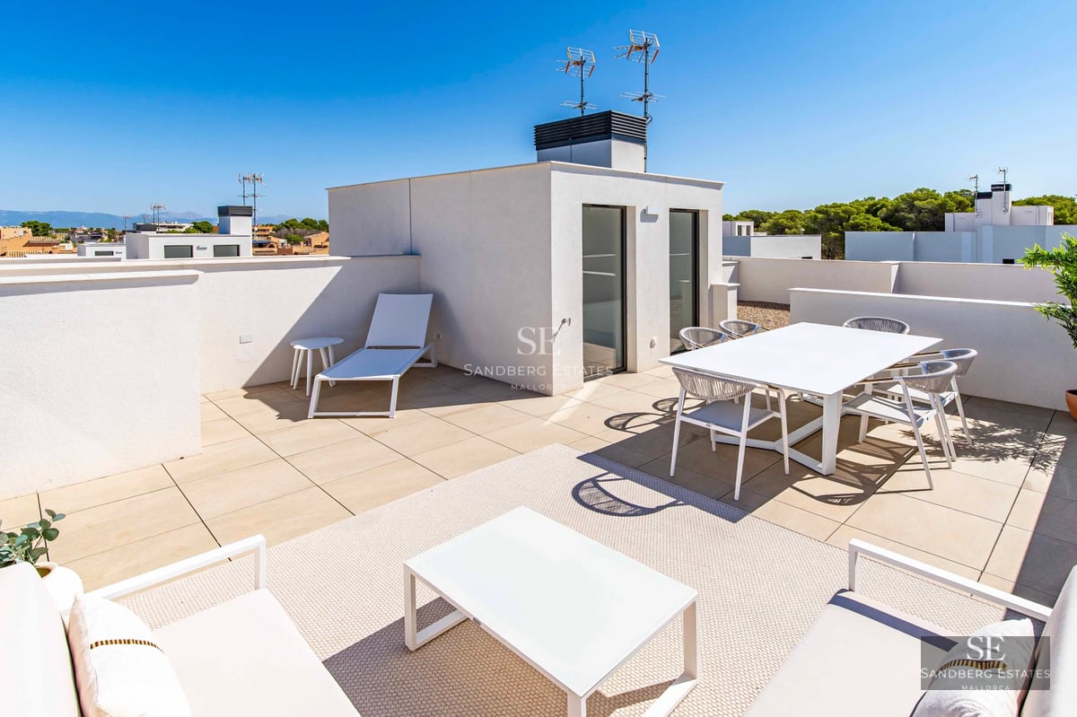Spacious terrace with wooden flooring, glass railing, panoramic sea view, and modern outdoor furniture. Natural lighting.