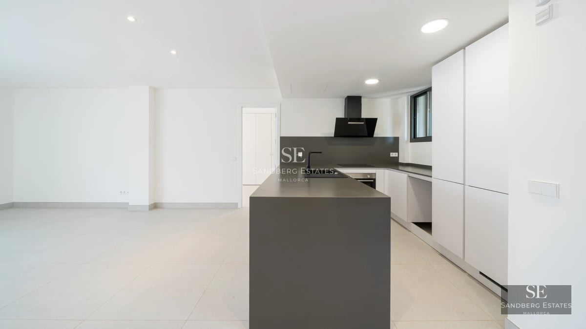 Spacious living room with large windows, light wood flooring, and stunning sea views. Modern furniture and abundant natural light.