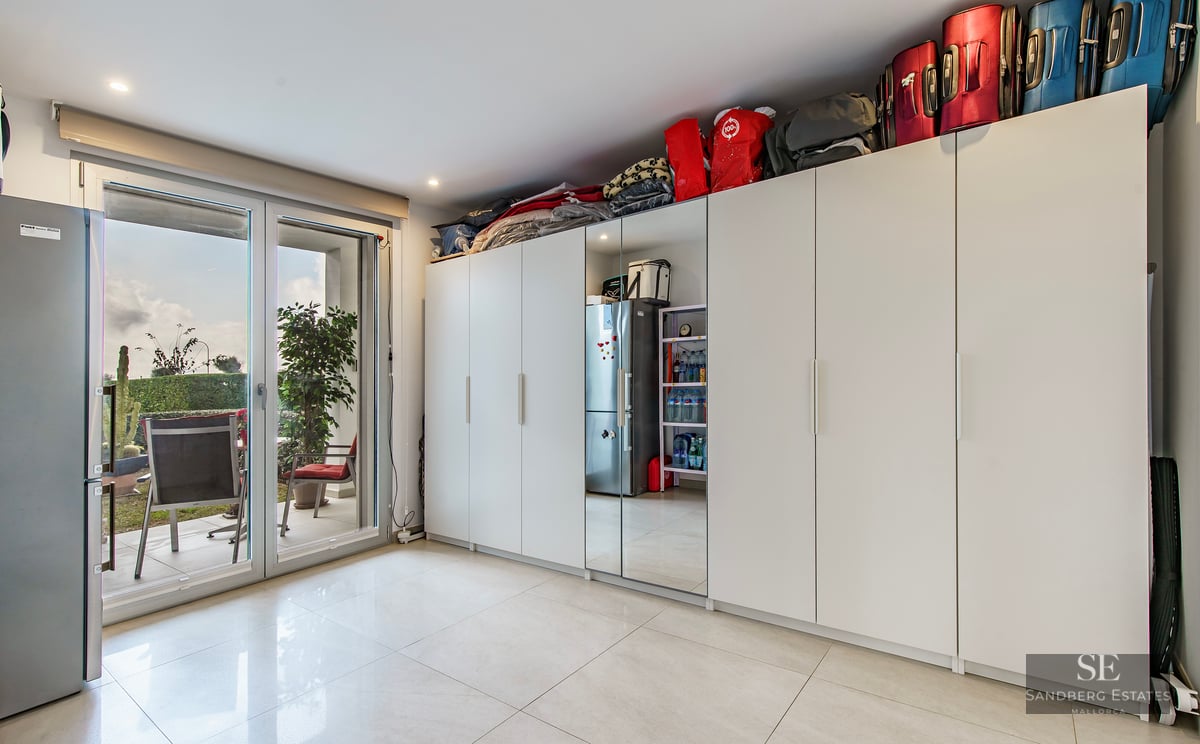 Bright room featuring large white wardrobes and glass doors leading to a furnished outdoor terrace.