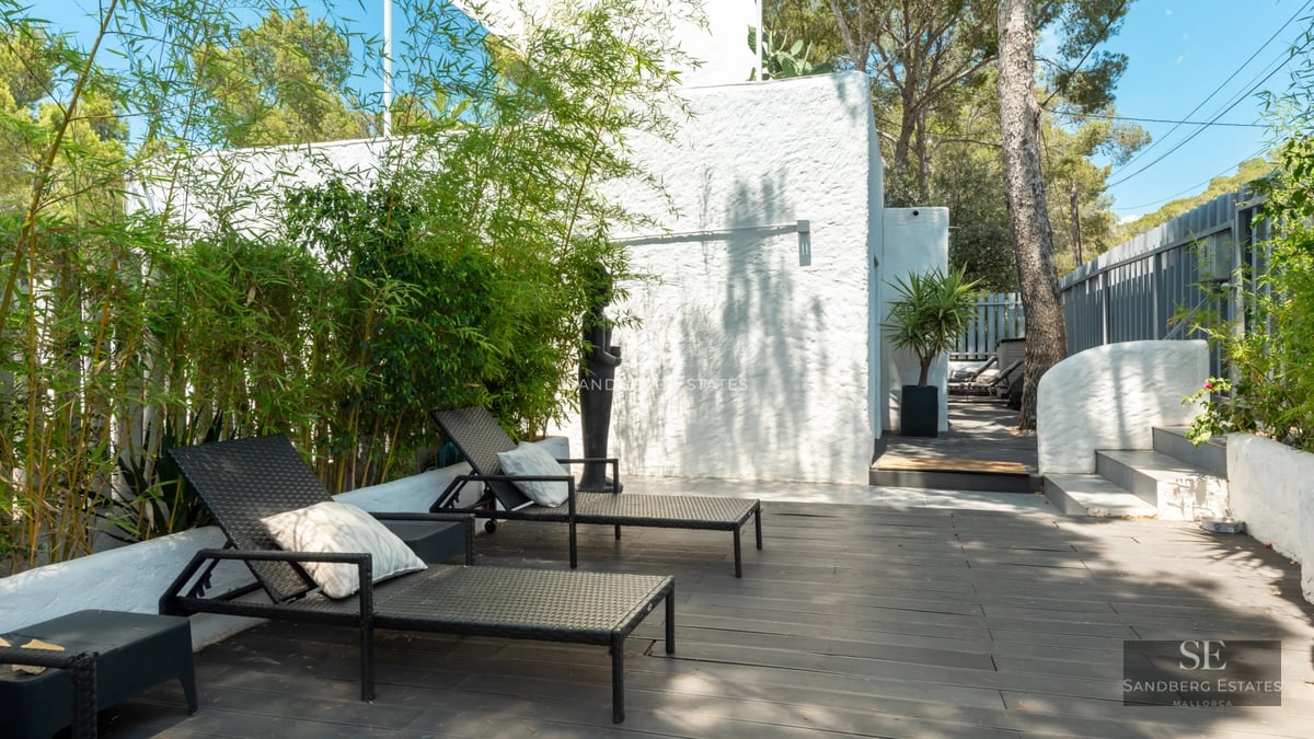 View of modern villa featuring infinity pool, sun loungers, manicured lawn, and minimalist architecture on a sunny day.