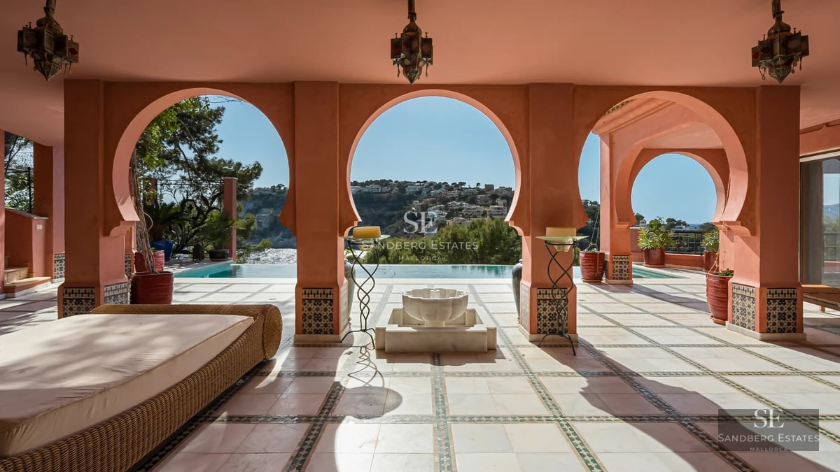 Bright living room featuring a modern fireplace, large windows overlooking the sea, minimalist decor, and designer furniture.