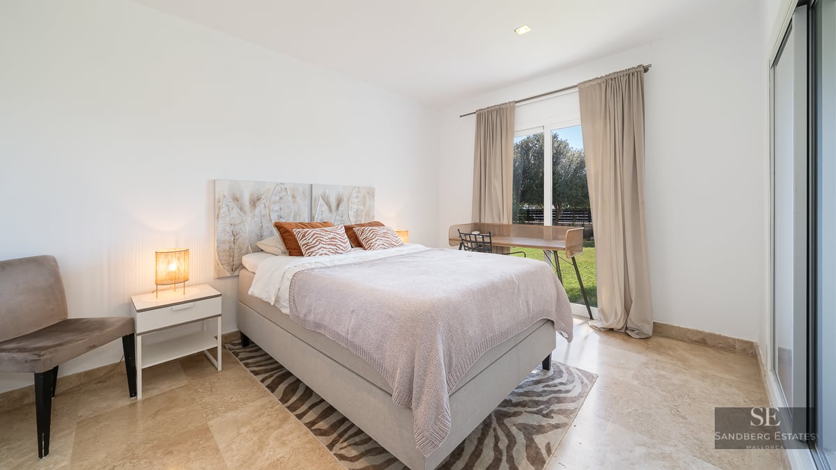 Modern bedroom with marble floors, a double bed, and a large glass door opening to a green garden.