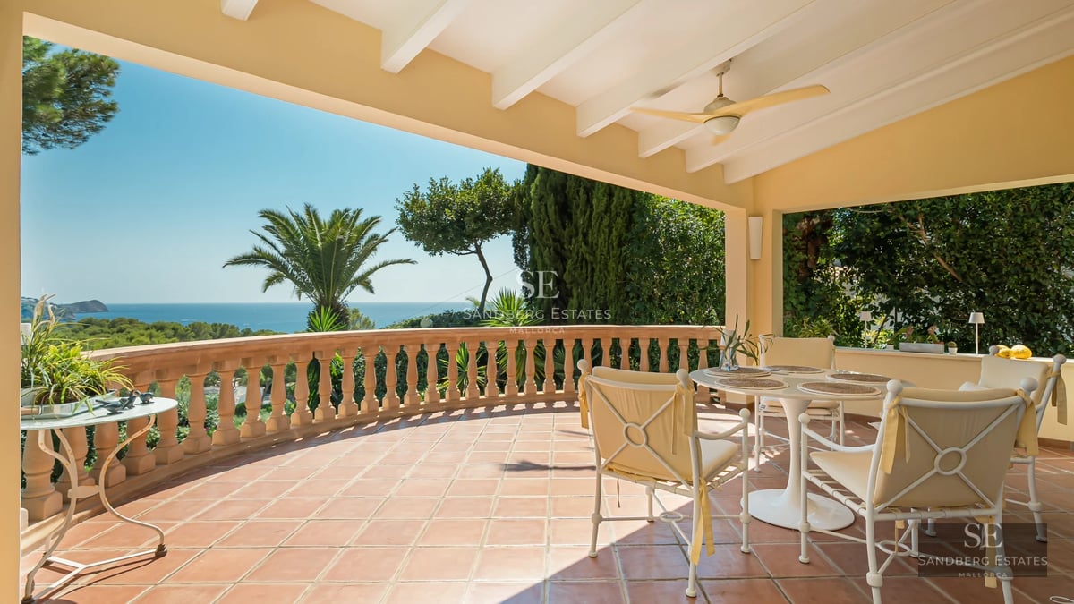 Spacious living room with panoramic windows, light wood floors, beige sofa, and stunning sea view. Modern and bright design.