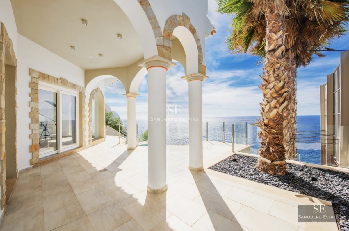 View of the pool surrounded by lawn, with the modern villa in the background. Large windows and minimalist design.