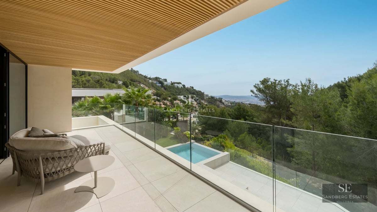 Spacious balcony with panoramic sea views. Modern and elegant furniture, wooden floor, and glass railing.