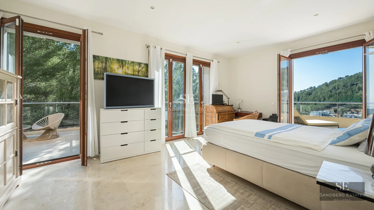 Bright living room with large windows and sea view. Gray sofa, modern coffee table, minimalist decor and wooden floor.