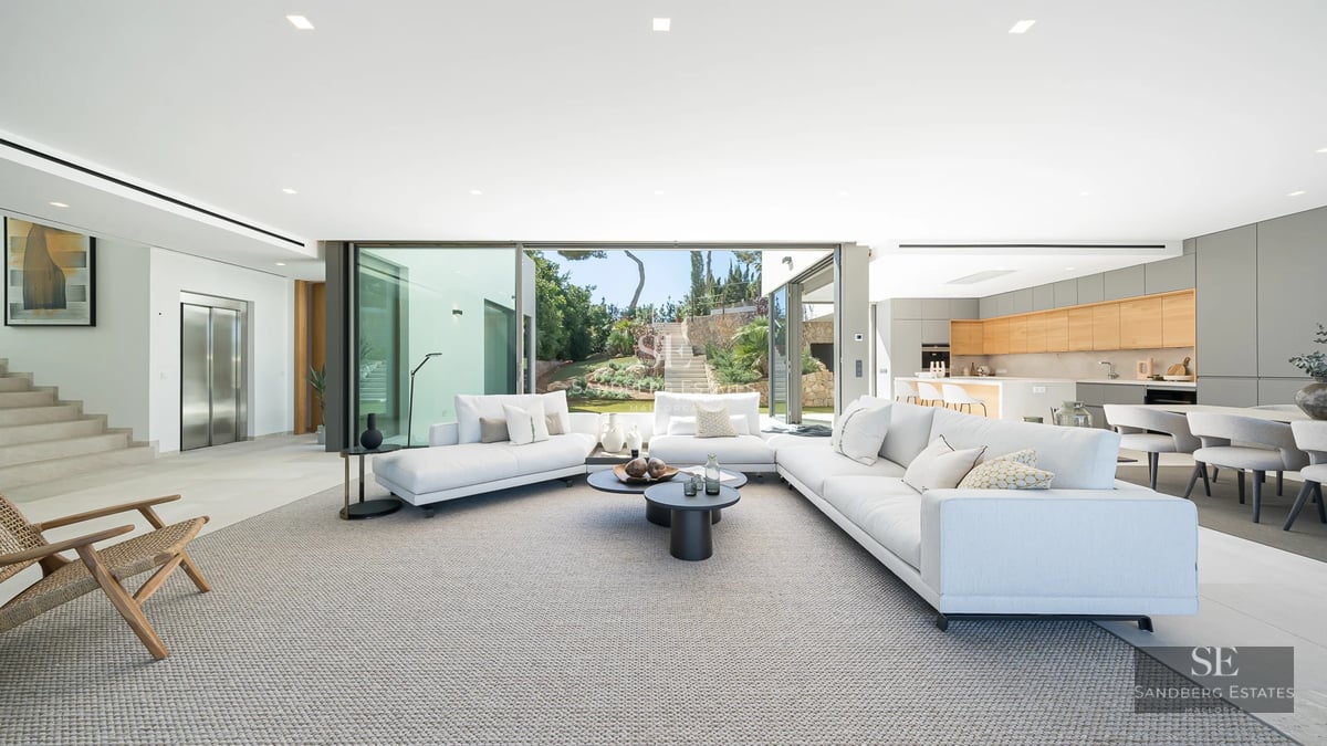 Aerial view of a modern villa with infinity pool, surrounded by gardens and spacious terraces. Minimalist and elegant architecture.