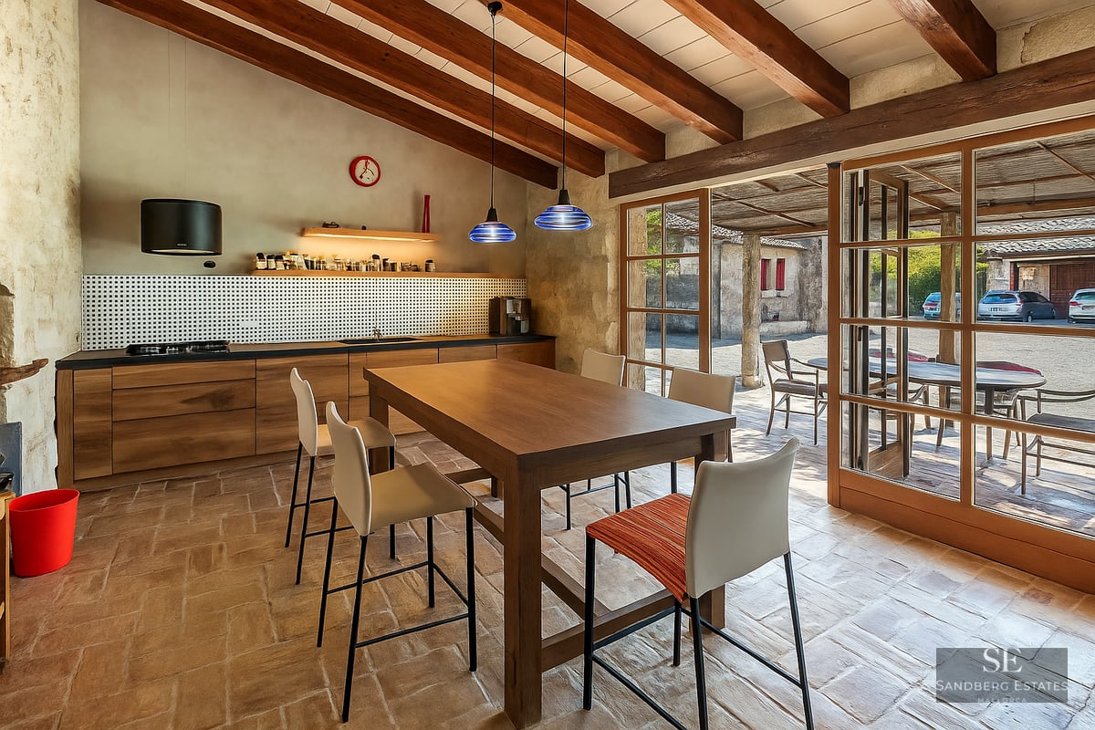 Kitchen with wooden beams, terracotta flooring, and large glass doors leading to an outdoor courtyard.