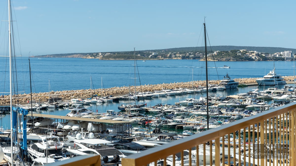 Panoramic view of a luxury marina with yachts and the blue Mediterranean sea from a terrace.