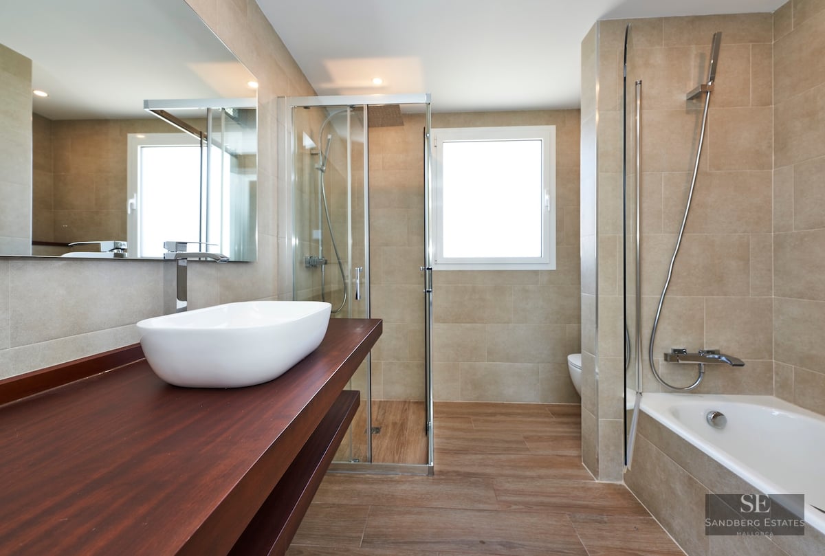 Modern bathroom featuring a white vessel sink on a wood vanity, a glass shower, and a built-in bathtub.
