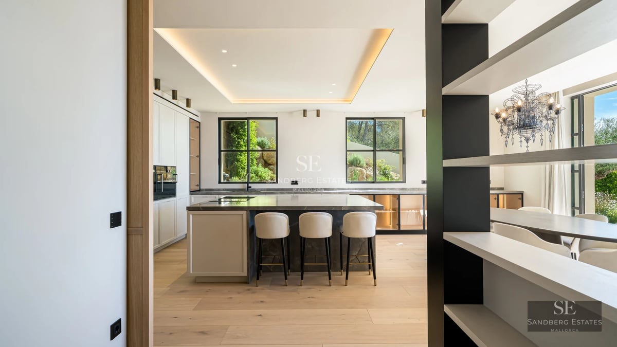 View of an infinity pool overlooking the sea from a modern villa. Loungers, umbrellas, and lush vegetation.