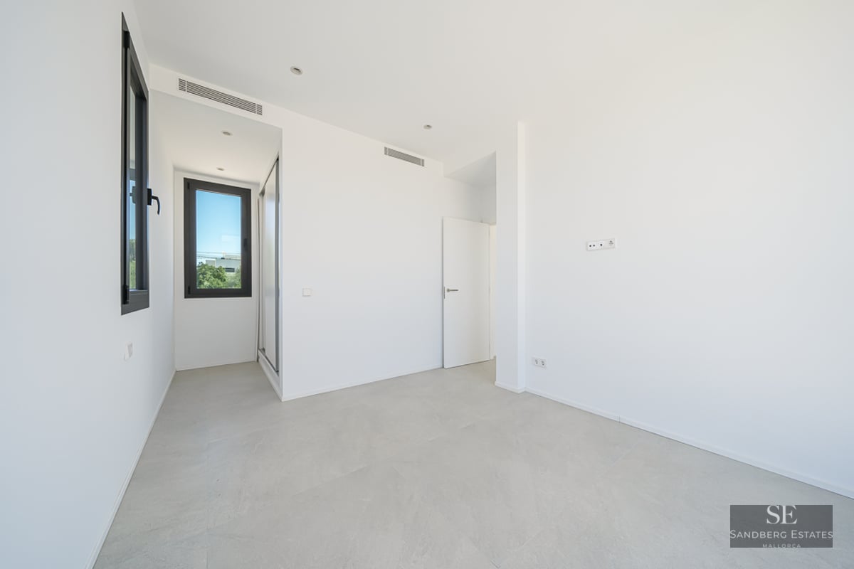 Empty room with white walls, light gray tile floors, and black-framed windows.
