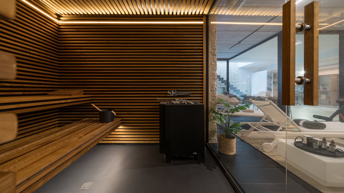 Interiör av en lyxig bastu med horisontella träribbor, integrerad LED-belysning och utsikt mot relaxavdelningen.