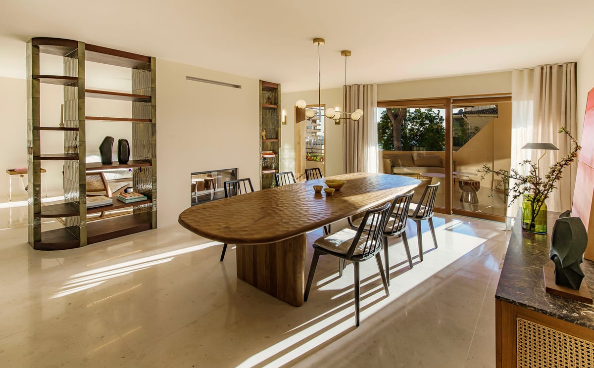 Sonniges Esszimmer mit strukturiertem Holztisch, schwarzen Stühlen, Marmorboden und Terrassenzugang.