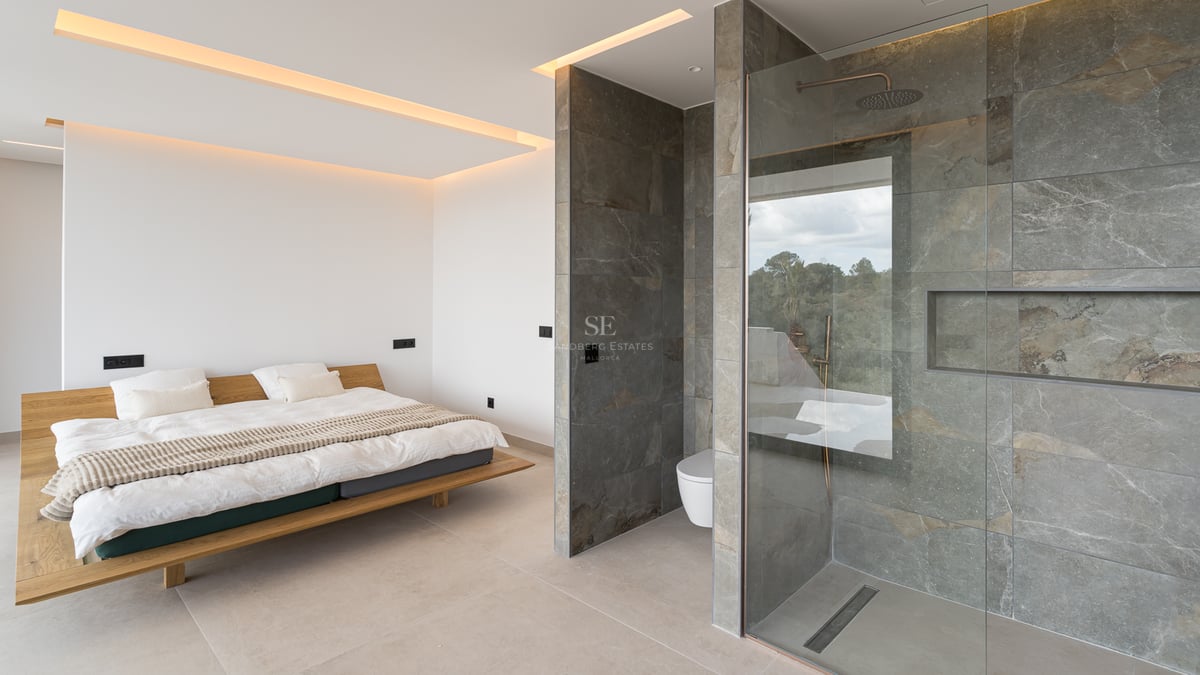 Modernes Schlafzimmer mit schwebendem Holzbett und offenem Bad mit grauen Steinfliesen und Glasdusche.