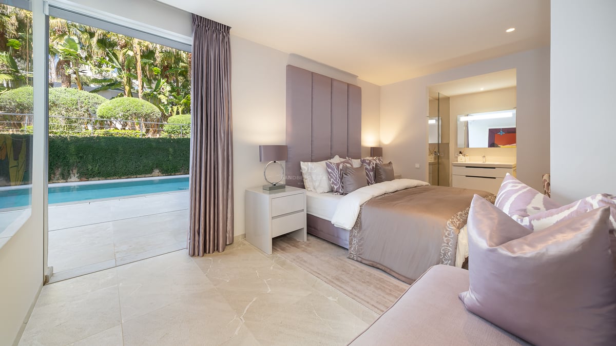 Modernes Schlafzimmer mit Doppelbett, gepolstertem Kopfteil, Marmorboden und direktem Zugang zum Außenpool.