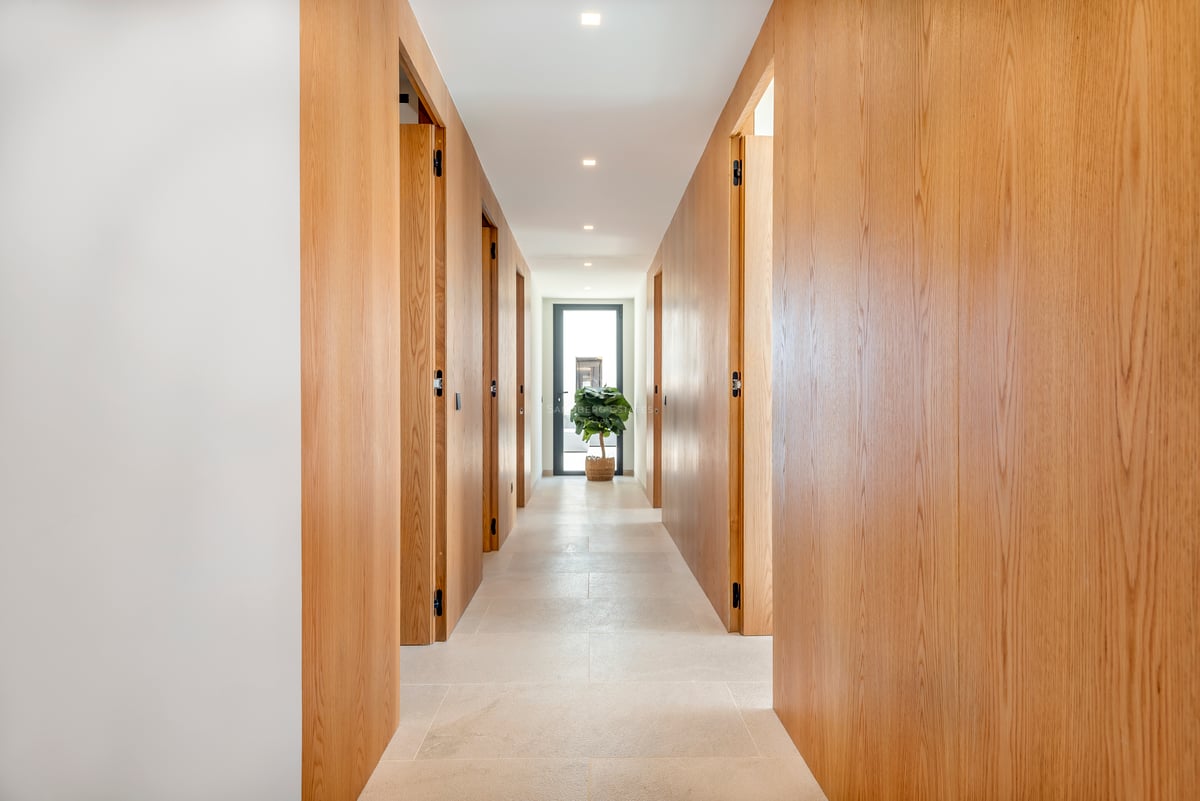 Couloir moderne lumineux avec des panneaux en bois de chêne du sol au plafond et des portes affleurantes.