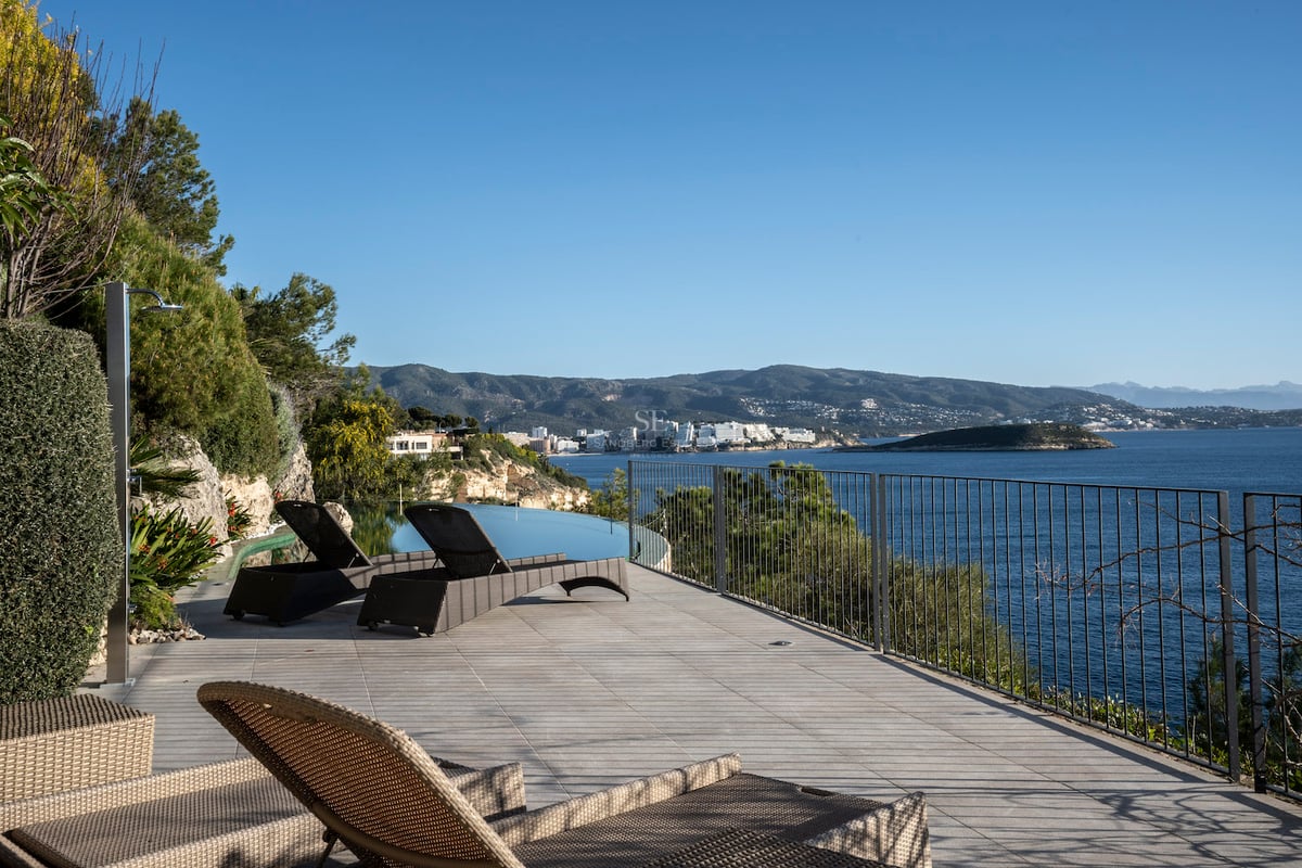 Luxuriöse Sonnenterrasse mit Liegen, Infinity-Pool und Panoramablick auf das Mittelmeer und die Berge.