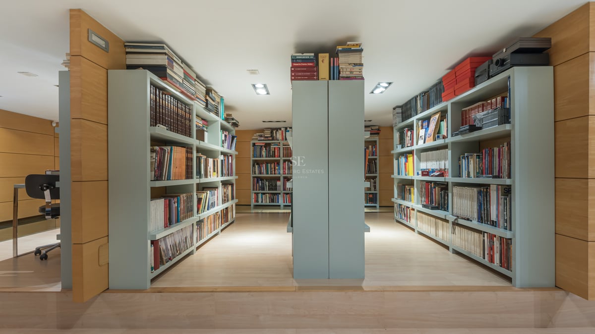 Bibliothèque moderne avec boiseries en chêne clair et étagères intégrées vert sauge.