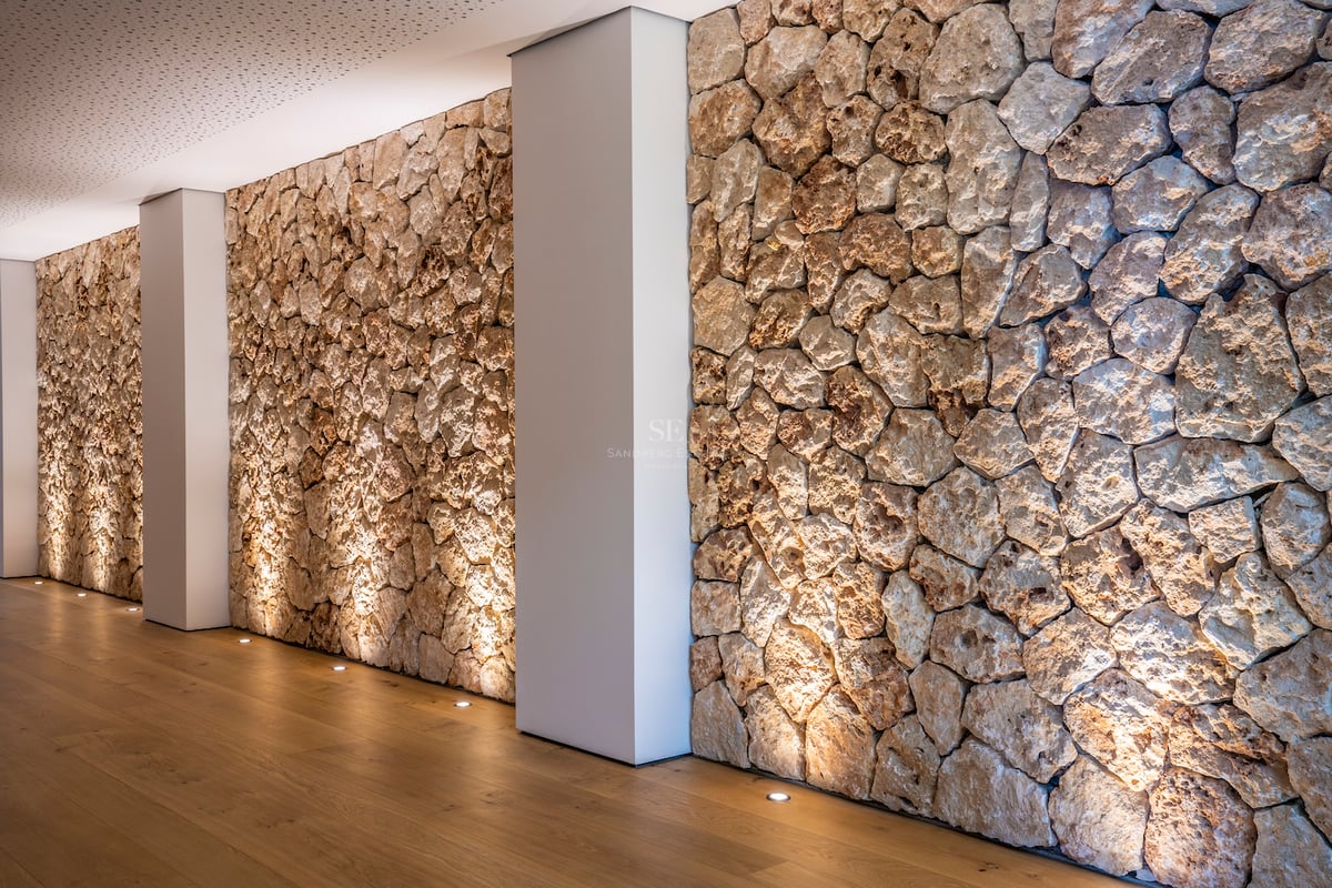 Innenflur mit rustikaler Natursteinwand, Bodenstrahlern und hellem Eichenparkett.