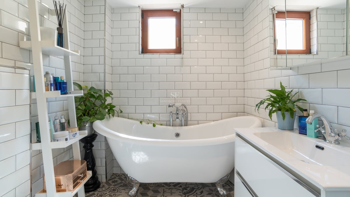 Salle de bains lumineuse avec baignoire sur pieds, carreaux de métro blancs et meuble vasque contemporain.