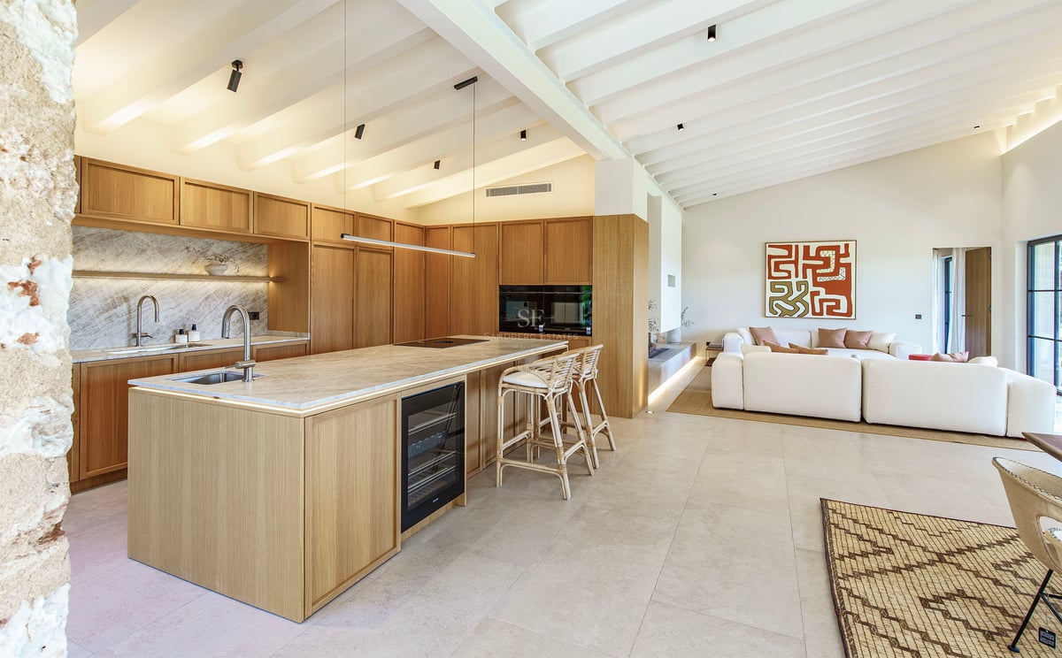 Moderne offene Küche mit hellen Holzschränken, Marmorinsel und weißer Balkendecke.