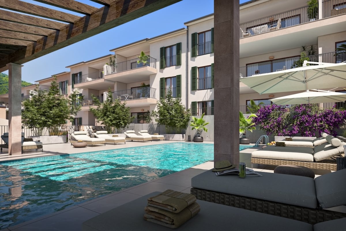 Modern pool med solstolar, parasoll och träpergola intill en exklusiv lägenhetsbyggnad.