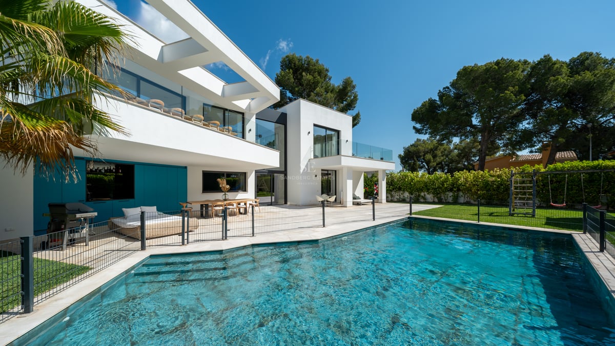 Extérieur de villa contemporaine blanche avec piscine, clôture de sécurité et terrasse couverte avec coin repas.