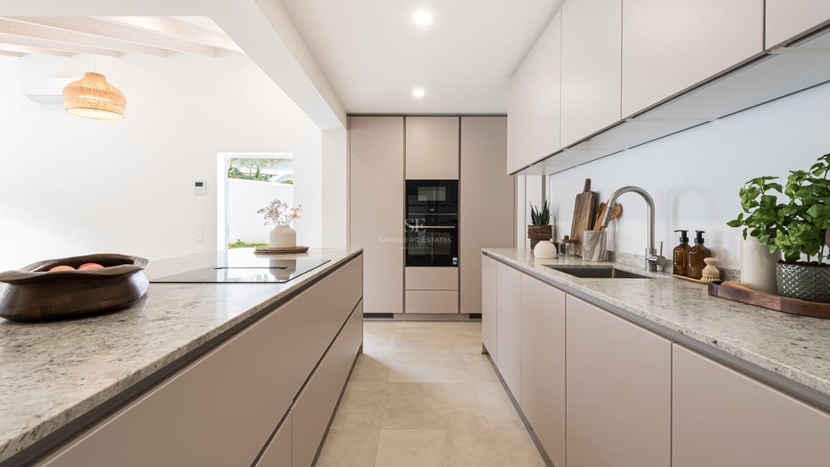 A contemporary beige kitchen featuring granite countertops, a center island, and integrated high-end appliances.