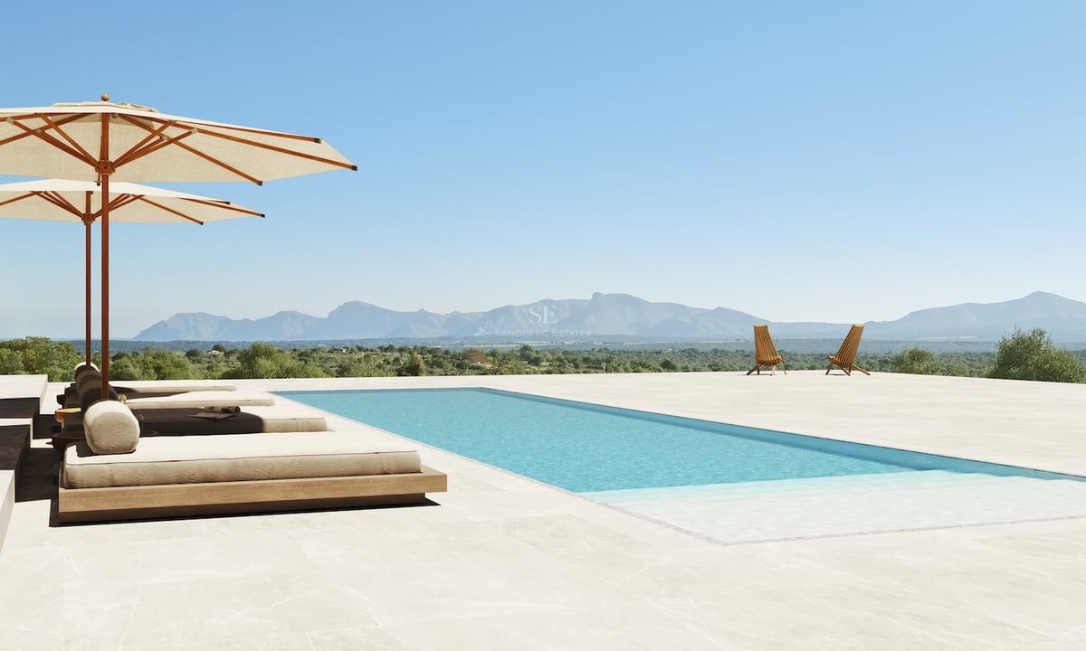 Piscine rectangulaire entourée de dalles en pierre, lits de jour de luxe et parasols avec vue lointaine sur les montagnes.