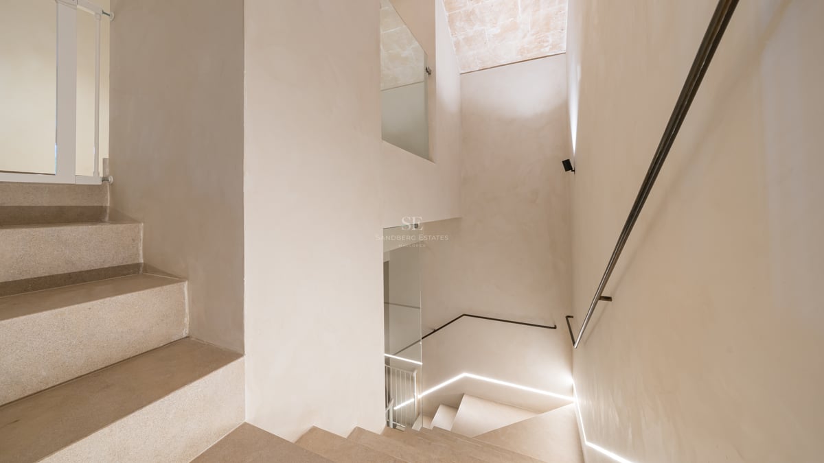 Escalier intérieur minimaliste avec marches en pierre claire, parois en verre et éclairage LED intégré au mur.