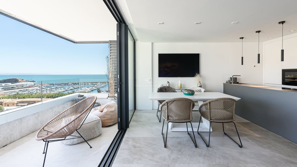 Modernes Esszimmer und Terrasse mit Glasgeländer mit Blick auf einen Jachthafen und das Mittelmeer.