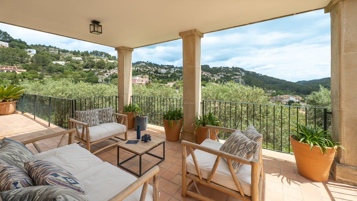 Terrasse couverte avec sol en terre cuite, mobilier en bois et vue sur les montagnes de Majorque.